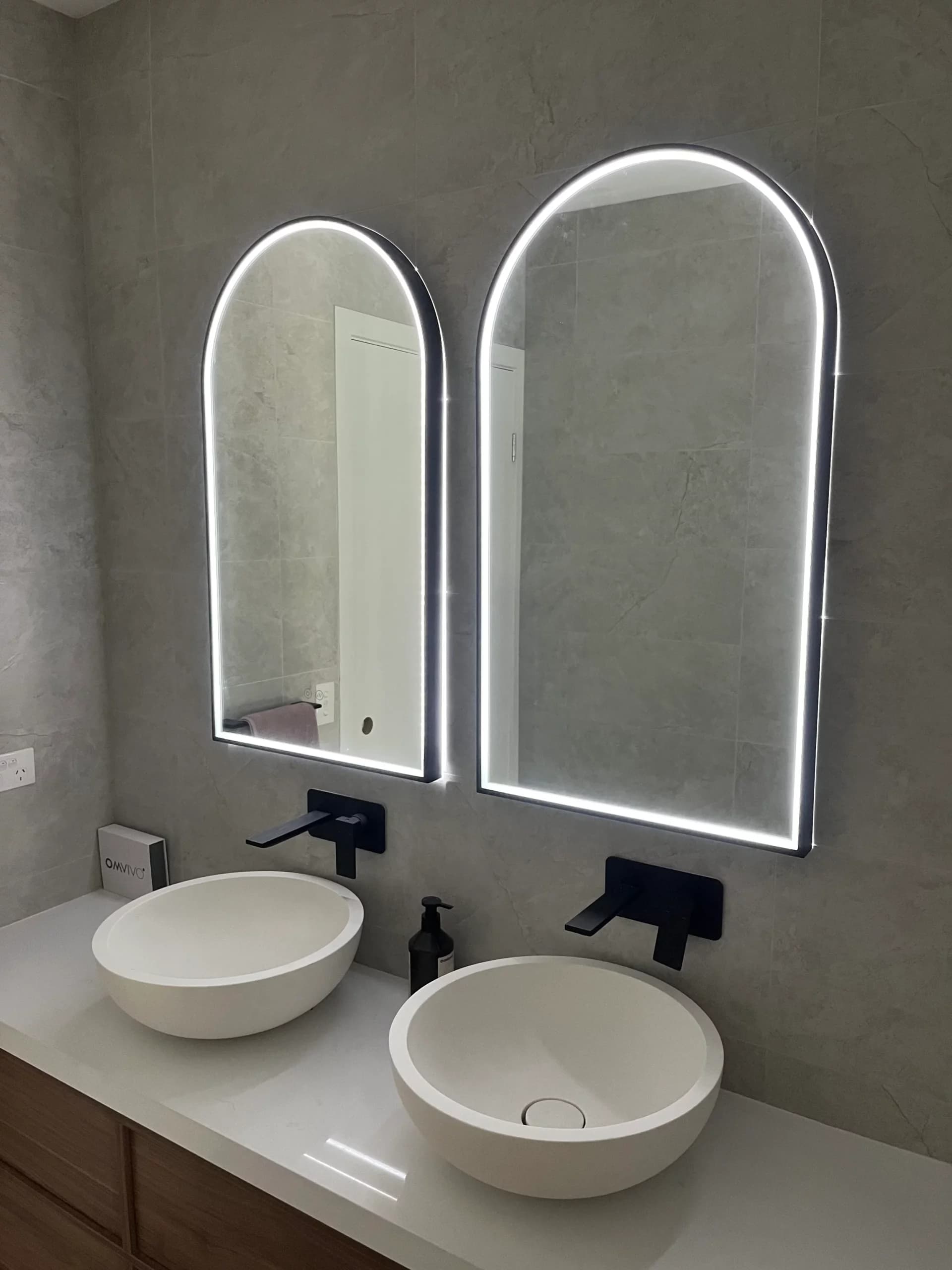 Backlit arched mirrors and vanity lighting installed by Goodwill Electrical